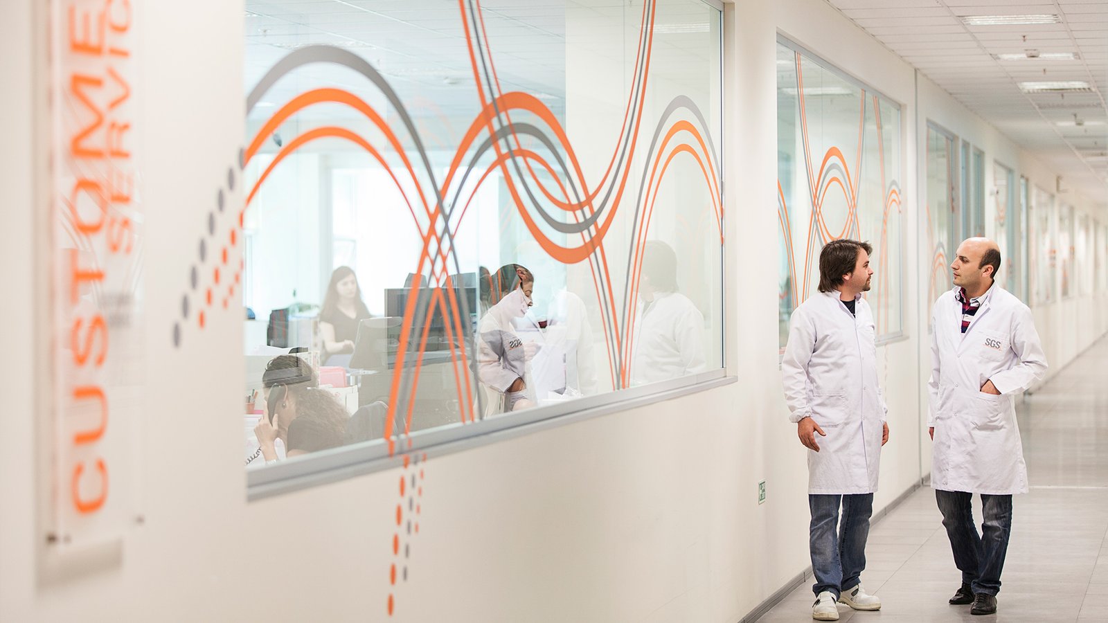 SGS laboratory specialists walking through a research and testing facility corridor