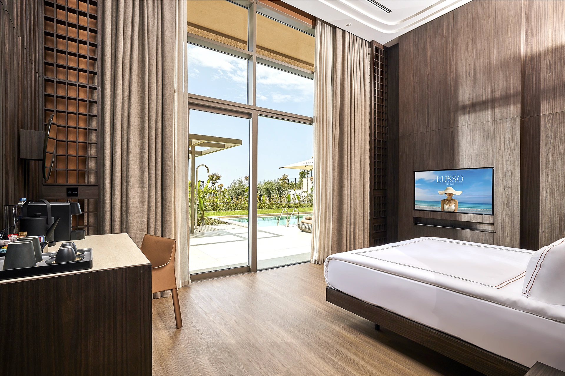Luxury guest room at Lusso Resort featuring floor-to-ceiling windows, contemporary interior design, premium bedding, and views of the Mediterranean landscape
