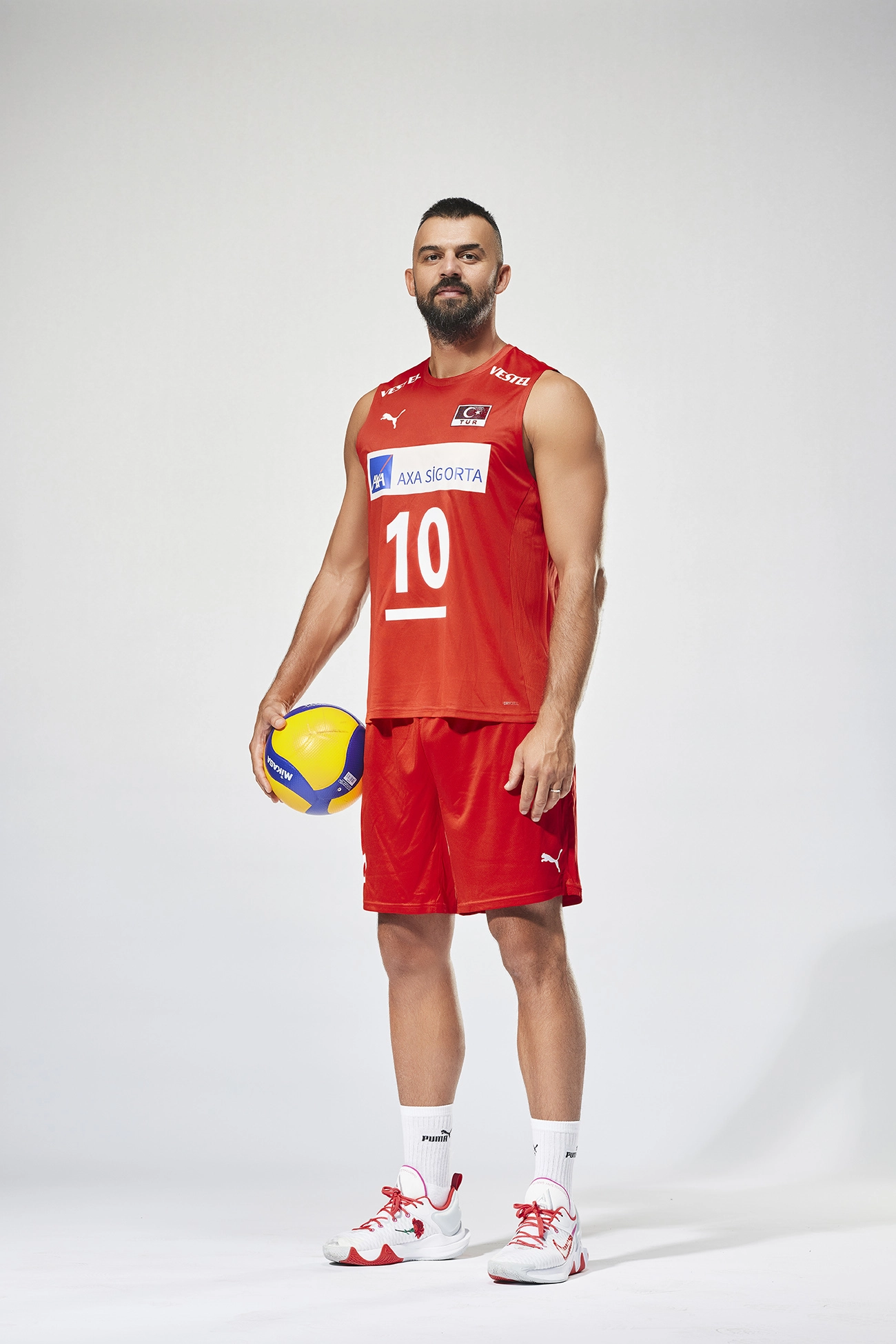 Professional portrait of Turkish national volleyball player Arslan Ekşi in the official Türkiye Men’s National Volleyball Team uniform, photographed for a Puma sportswear campaign on a white studio background.