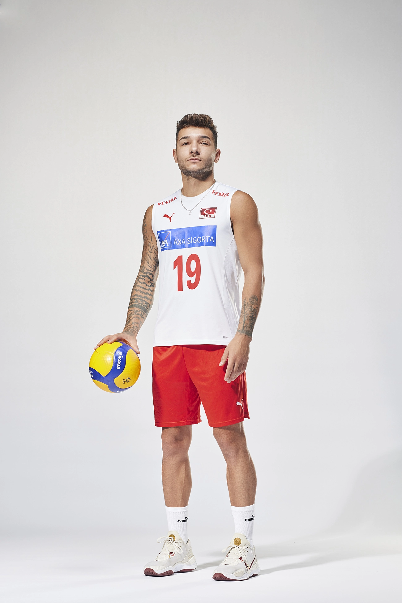 Professional portrait of Turkish national volleyball player Berkay Bayraktar in the official Türkiye Men’s National Volleyball Team uniform, photographed for Puma sportswear campaign on a white studio background.