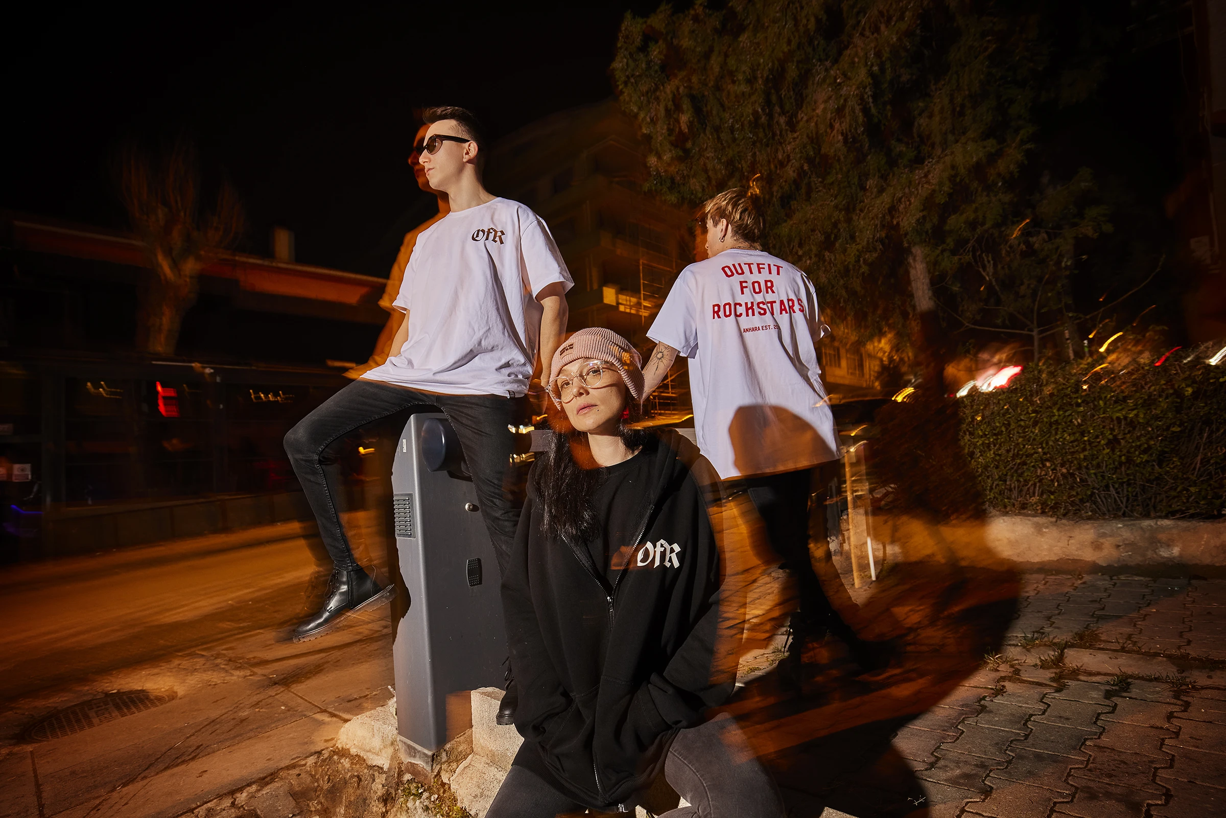 Group of young models posing outdoors at night during a contemporary fashion campaign shoot.