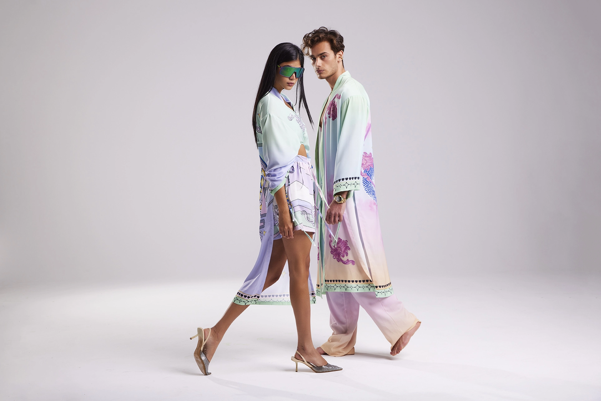 Two fashion models wearing flowing pastel garments walking together during a Je Te Veux studio fashion campaign.