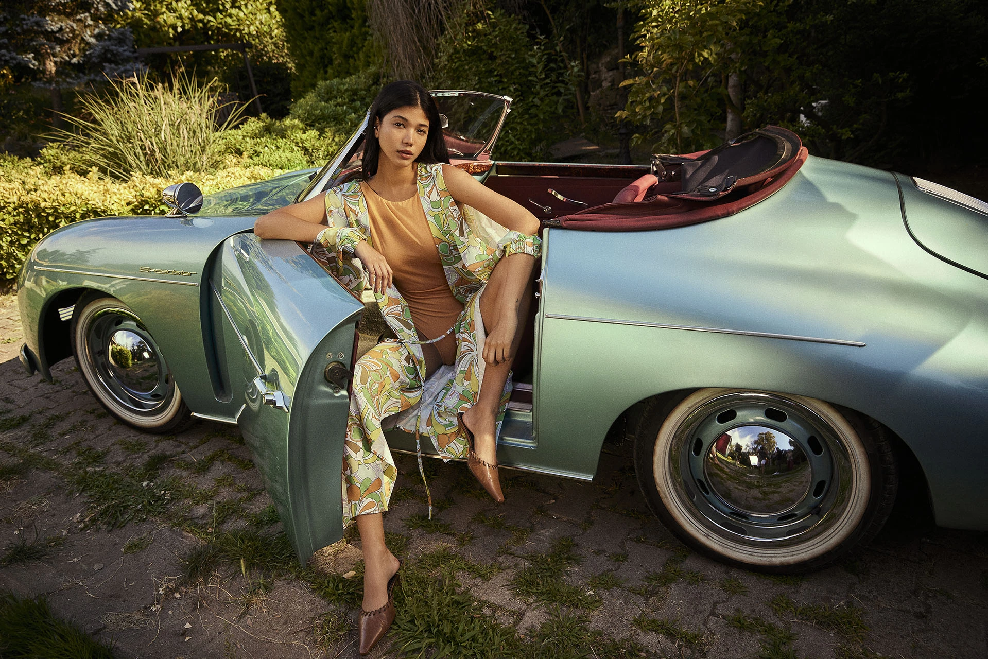 Fashion model posing beside a vintage convertible car during a Je Te Veux outdoor fashion campaign.
