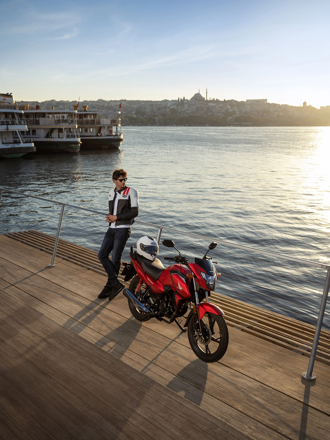 Professional automotive photography featuring a Honda motorcycle and rider in a modern architectural setting. The image highlights urban mobility, rider lifestyle, motorcycle design, and transportation advertising photography with a dynamic commercial approach.