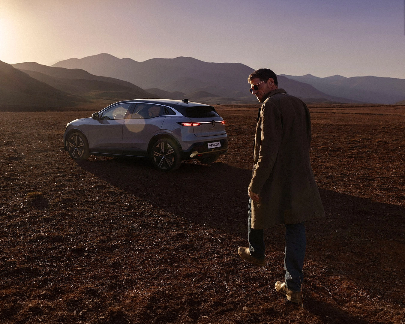 Renault Megane E-Tech electric vehicle and driver in mountain landscape at sunset