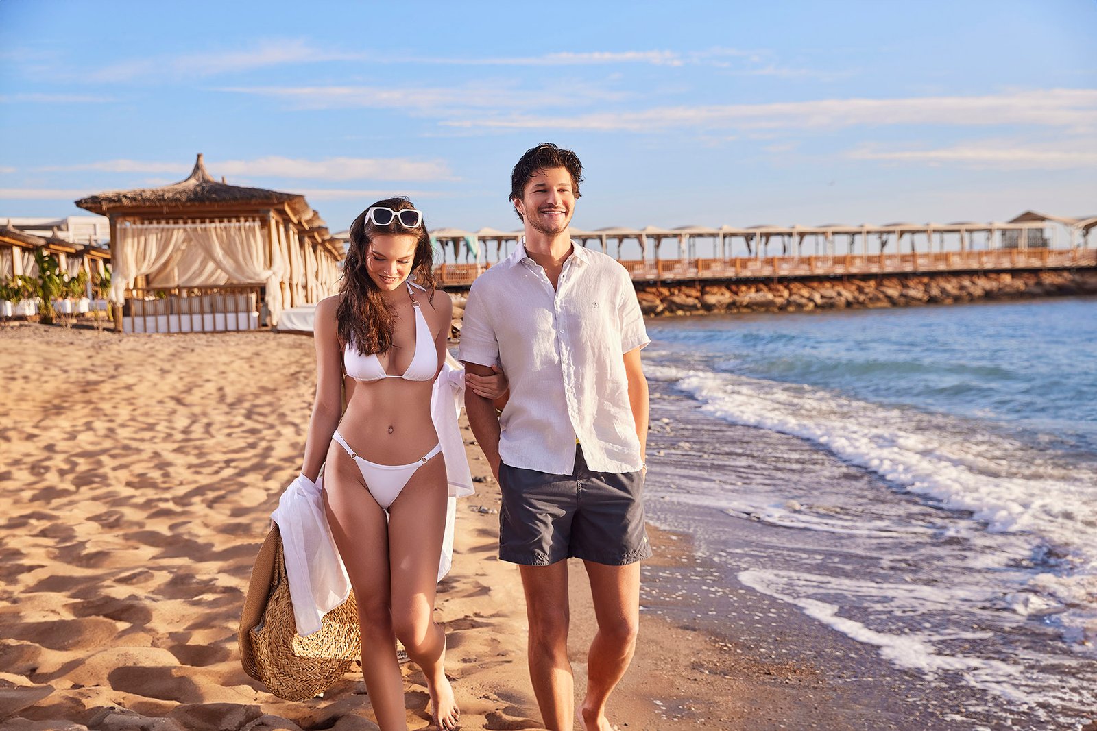 Couple walking on the beach at Rixos Sungate Hotel in Antalya during golden hour, showcasing luxury resort lifestyle and seaside vacation experience.