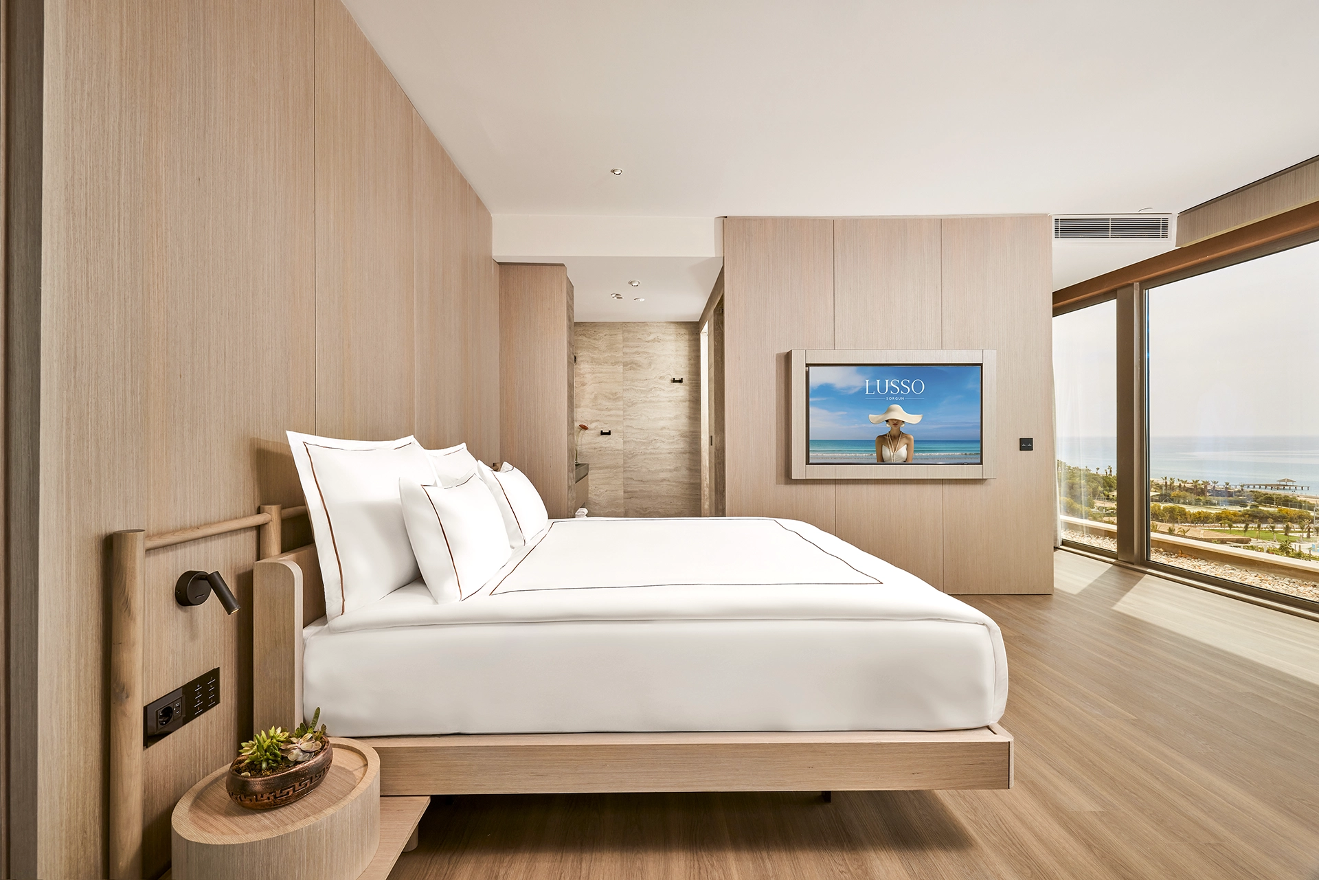 Luxury guest room at Lusso Resort with contemporary interior design, premium bedding, floor-to-ceiling windows, and Mediterranean sea views