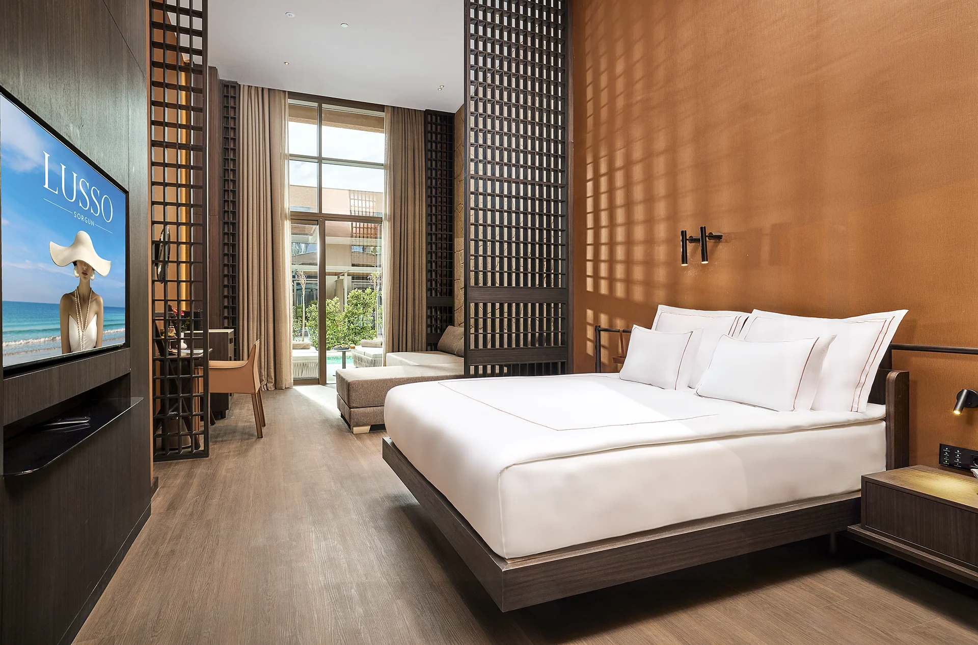 Luxury guest room at Lusso Resort featuring contemporary interior design, premium bedding, warm wood finishes, and a private terrace view