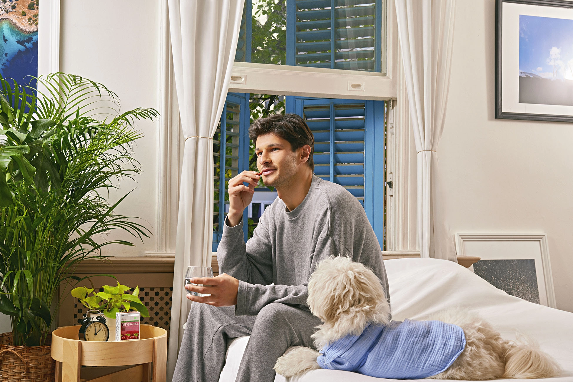 Man relaxing with his dog while taking a daily supplement in a comfortable home environment, wellness lifestyle campaign.