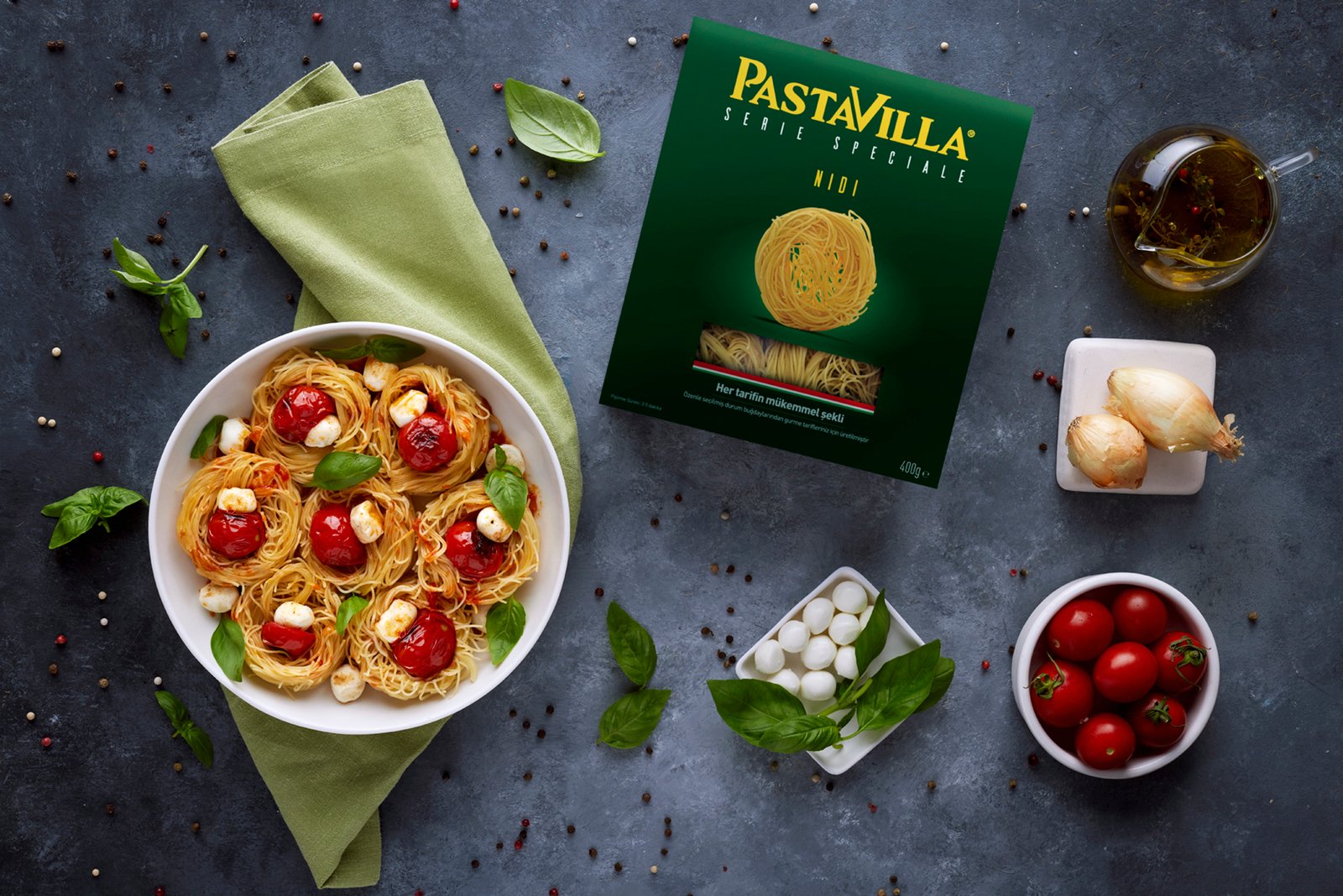 Professional commercial food advertising photographs by Sinan Niyazi Kutsal showcasing a Pastavilla Nidi pasta box packaging flat lay and a white bowl of prepared nested pasta being served with a spatula.
