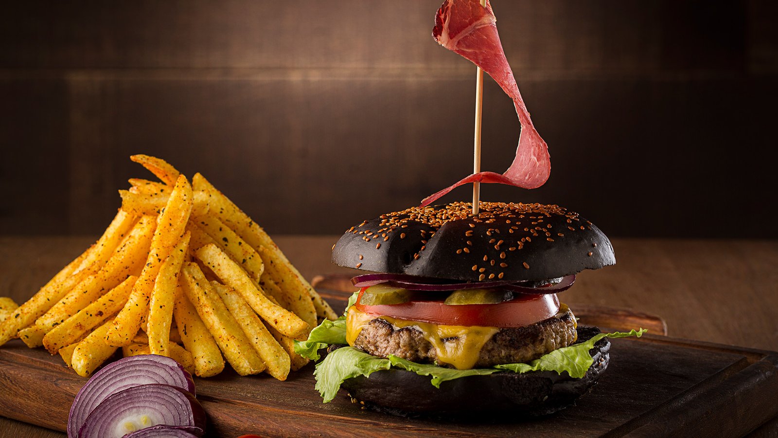Professional commercial food advertising photographs by Sinan Niyazi Kutsal showcasing a rich spread of gourmet mini slider burgers with spices, and a close-up of a charcoal black bun cheeseburger with seasoned french fries on a wooden board.