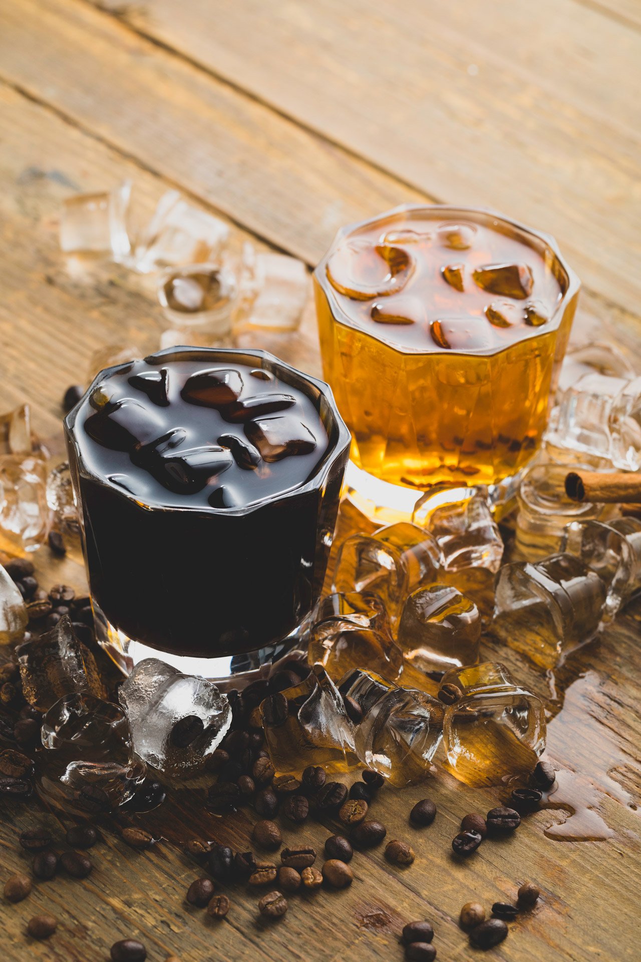 Professional commercial beverage advertising photographs by Sinan Niyazi Kutsal capturing freshly poured artisan coffee cups surrounded by roasted beans, and specialty cold brew coffee bottles on a sleek modern cafe table.