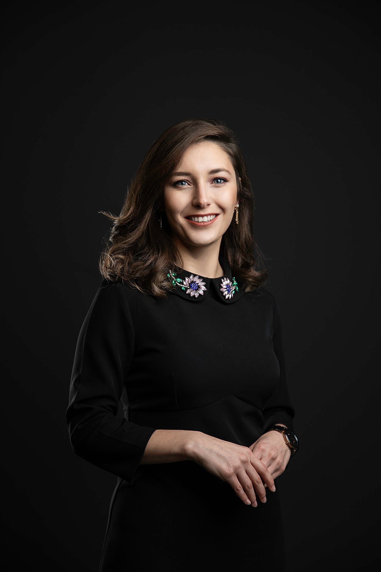 Professional studio portrait of a company team member photographed against a dark background with controlled lighting.