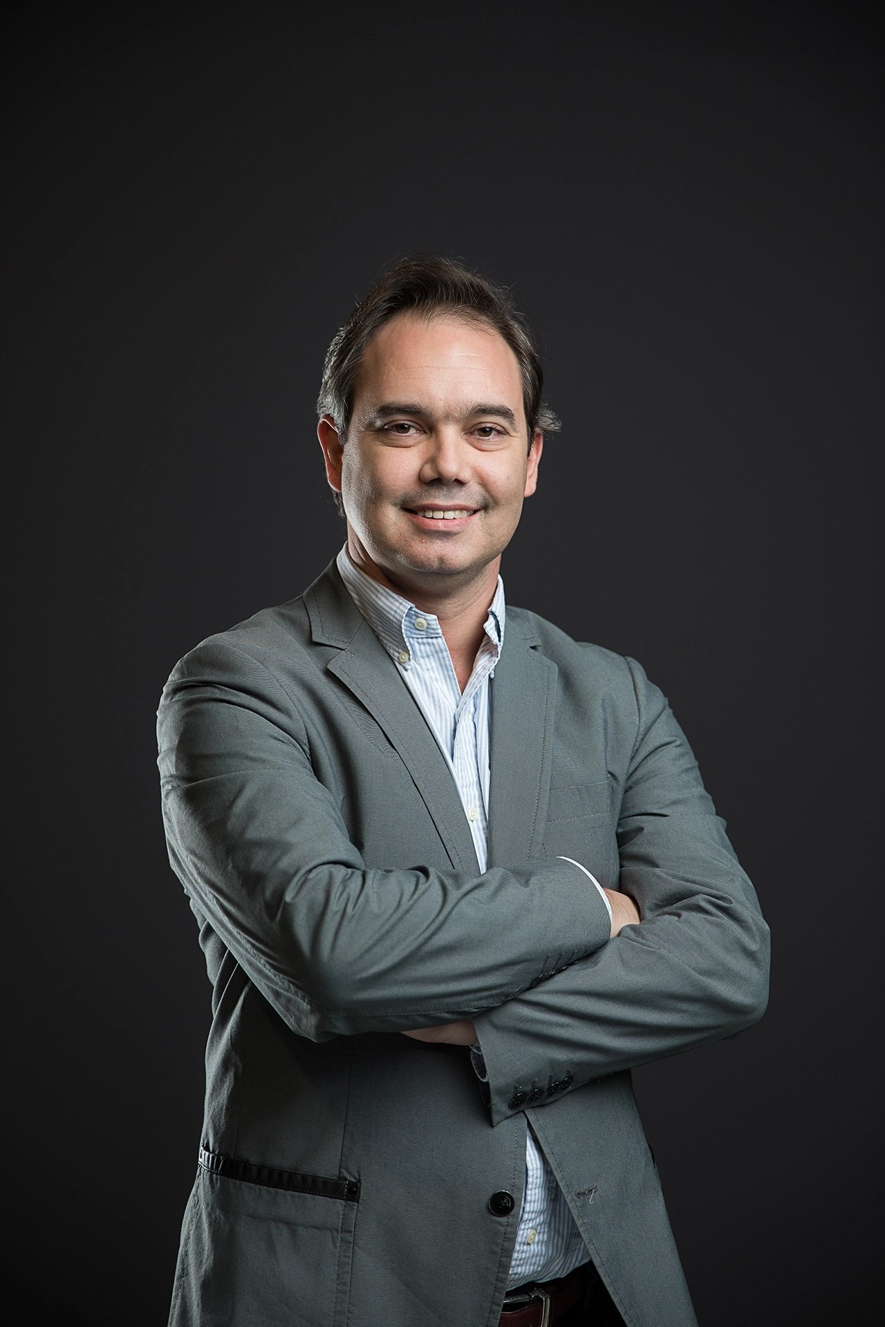 Professional studio portrait of a company team member photographed against a dark background with controlled lighting.