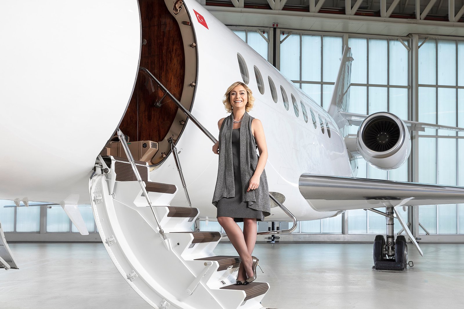 Senior aviation executive standing beside a private business jet inside an aircraft hangar during an editorial portrait session for Aviation Turkey Magazine.