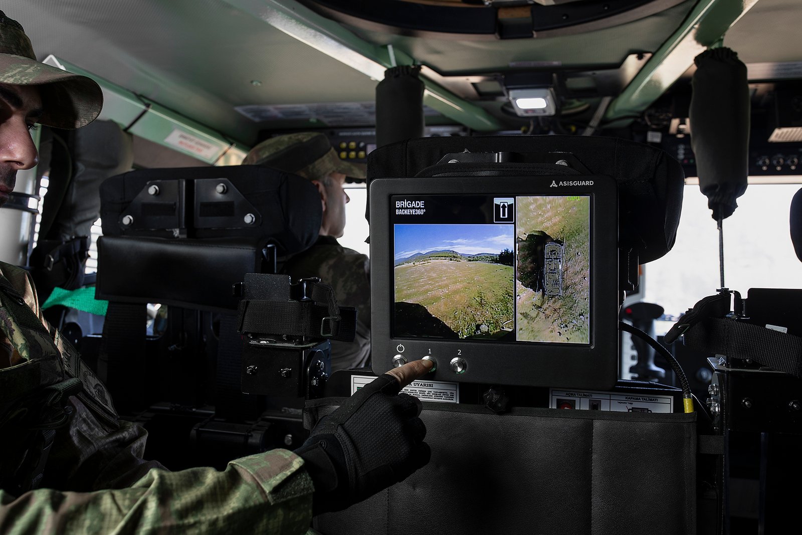 Professional commercial defense product photographs by Sinan Niyazi Kutsal for ASISGUARD, showcasing rugged military vehicle display monitors, armored vehicle intercommunication boxes, and multi-channel tactical screens over a clean studio setup.