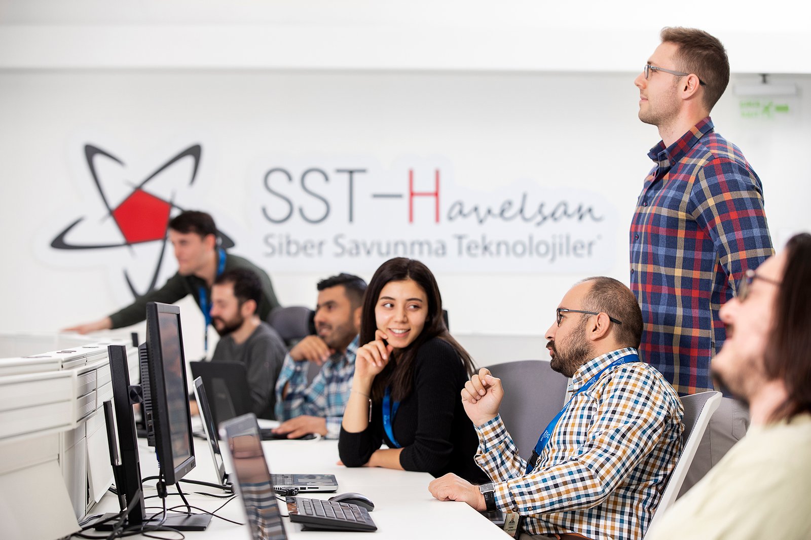 Professional commercial corporate photographs by Sinan Niyazi Kutsal for Havelsan, capturing tech engineers and corporate professionals monitoring advanced digital screens, coding, and testing simulation units inside modern software development laboratories.