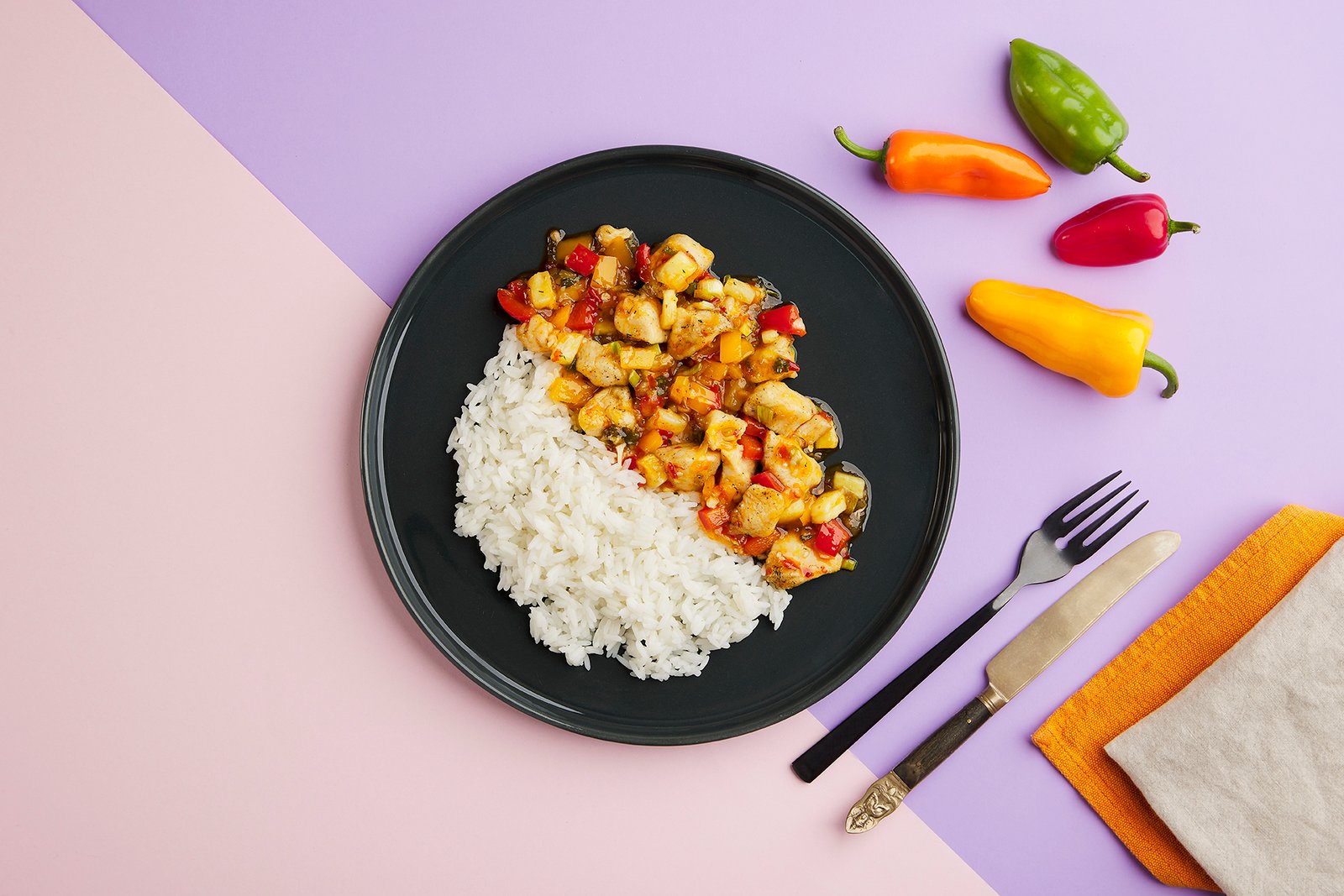 Professional commercial food advertising photograph by Sinan Niyazi Kutsal for Tarifte, featuring a wide top-down view of multiple plates of chicken, steak, and vegetables arranged around a large orange circular brand logo on white wood boards.