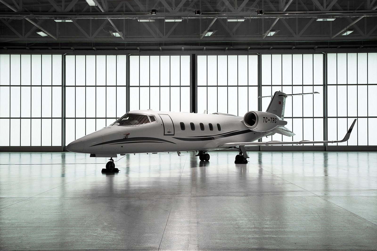 Professional commercial aviation photographs by Sinan Niyazi Kutsal showcasing a luxury private jet charter fleet and flight crew personnel inside a brightly lit hangar at Esenboga Airport.