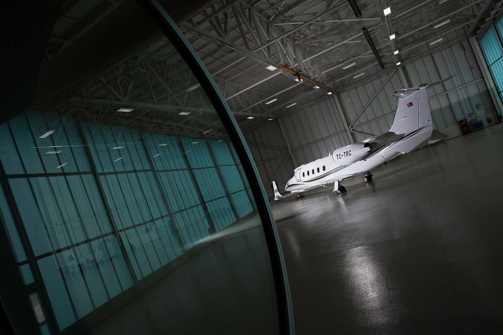 Professional commercial aviation photographs by Sinan Niyazi Kutsal showcasing a luxury private jet charter fleet and flight crew personnel inside a brightly lit hangar at Esenboga Airport.