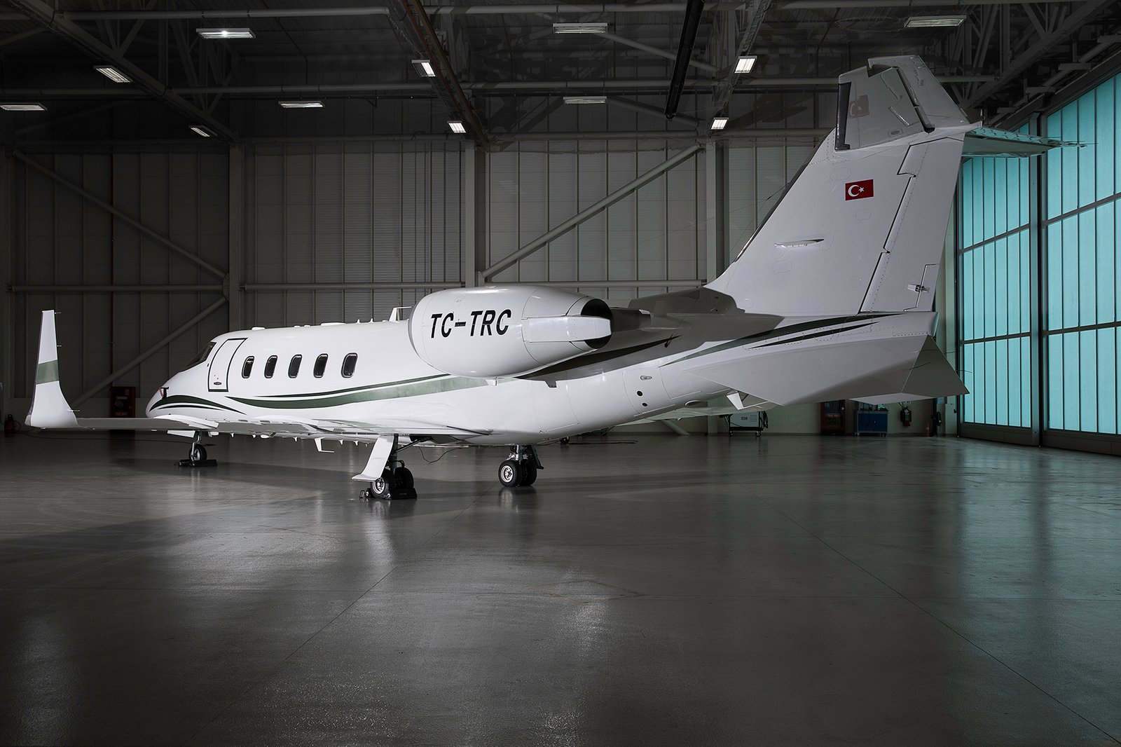 Professional commercial aviation photographs by Sinan Niyazi Kutsal showcasing a luxury private jet charter fleet and flight crew personnel inside a brightly lit hangar at Esenboga Airport.