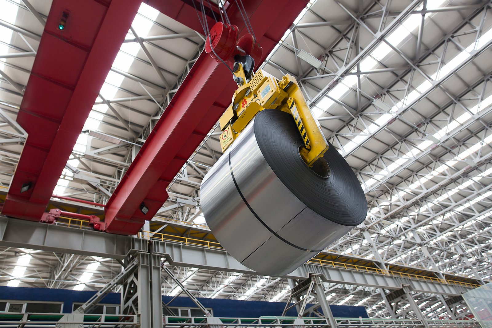 Professional commercial industrial photographs by Sinan Niyazi Kutsal for Gazi Metal capturing plant engineers operating automated console panels, a large overhead crane hoist picking up a steel coil, and rows of metal sheets in a warehouse.