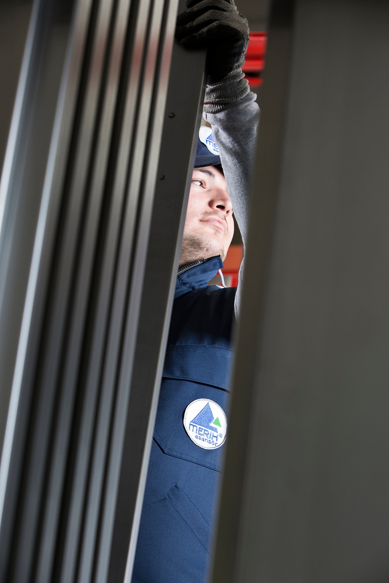 Professional commercial industrial photographs by Sinan Niyazi Kutsal for Merih Elevator, capturing operators in navy blue company uniforms handling steel sheets at a bending machine and monitoring a laser cutting enclosure throwing bright sparks.