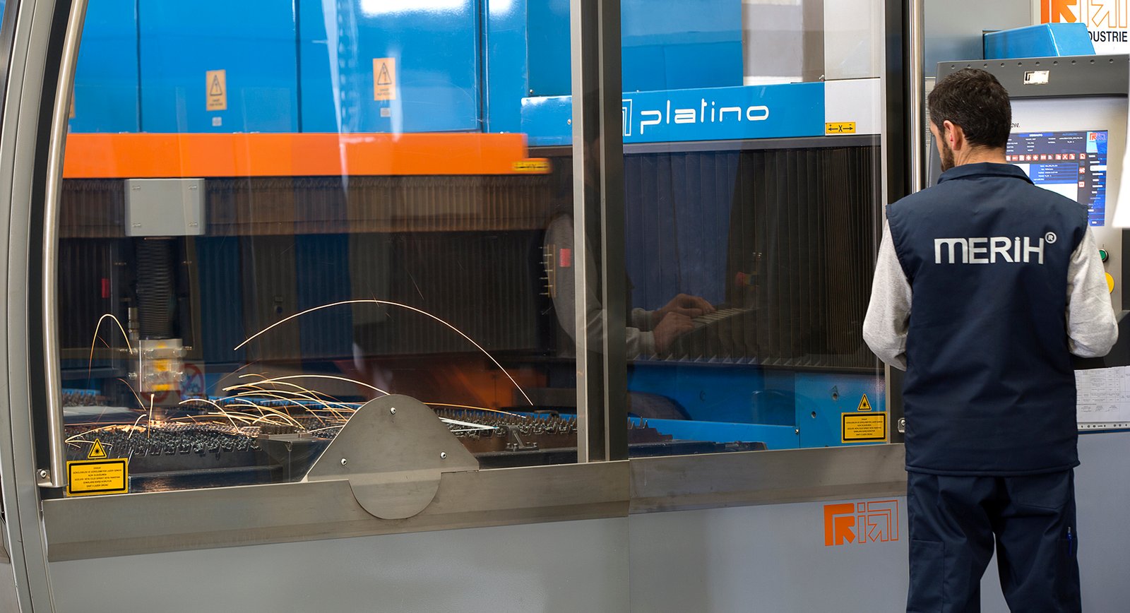 Professional commercial industrial photographs by Sinan Niyazi Kutsal for Merih Elevator, capturing operators in navy blue company uniforms handling steel sheets at a bending machine and monitoring a laser cutting enclosure throwing bright sparks.