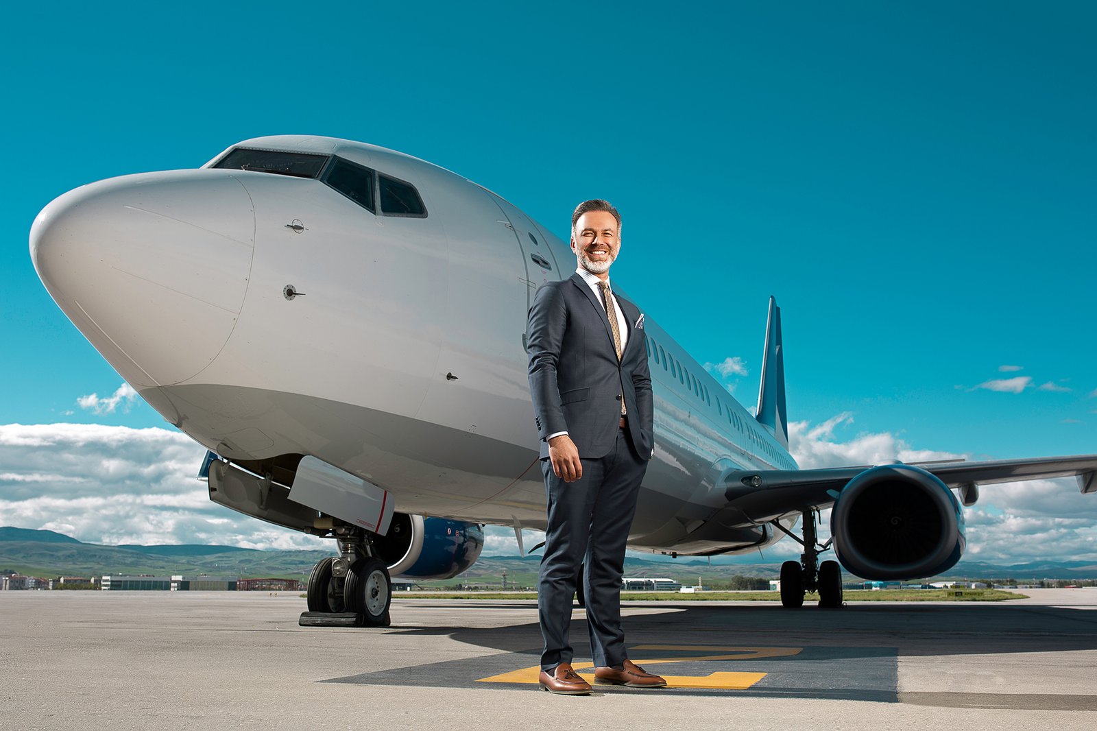Ferhat Yenibertiz standing beside business aircraft and helicopter during an executive aviation portrait session photographed for Aviation Turkey Magazine.
