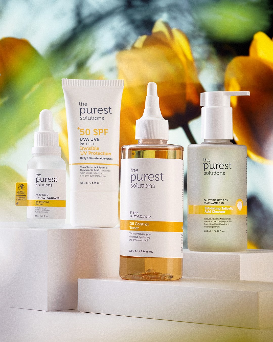 Professional commercial product advertising photographs by Sinan Niyazi Kutsal for The Purest Solutions, showcasing premium skincare serums, toners, and sunscreen tubes arranged elegantly on white geometric props with water drops.