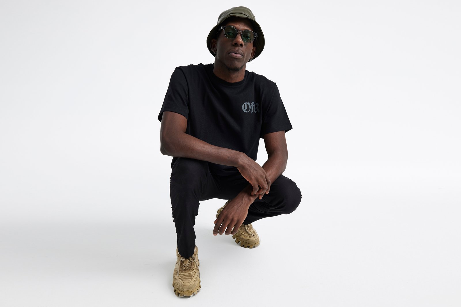 Professional commercial fashion studio photographs by Sinan Niyazi Kutsal for Outfit for Rockstars, capturing young models in black graphic t-shirts and hoodies posing against clean white and dramatic red backbones with an electric guitar.